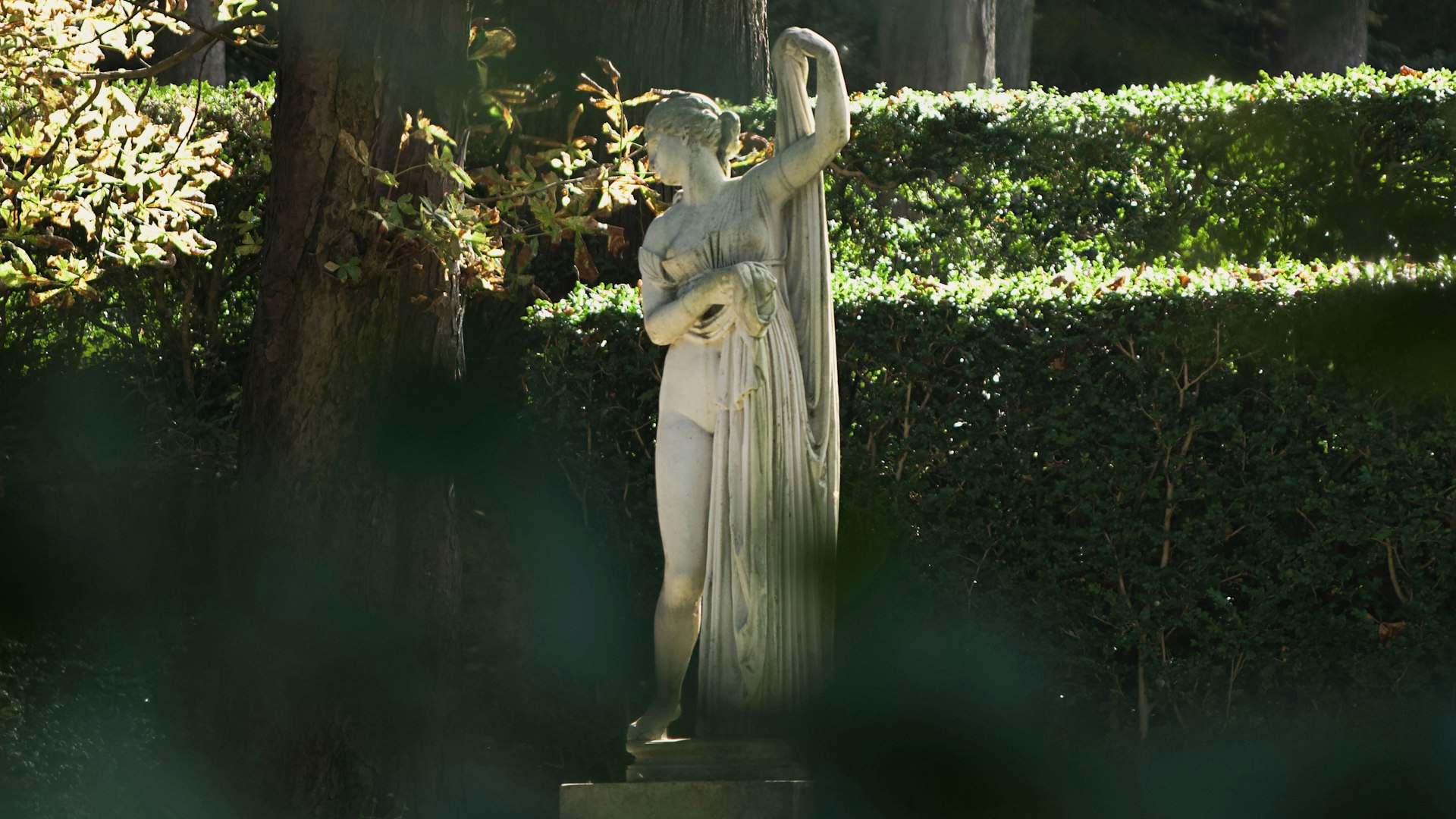 A statue of a woman holding a bird in a park